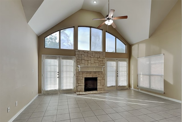 unfurnished living room featuring french doors, light tile patterned floors, ceiling fan, and a stone fireplace