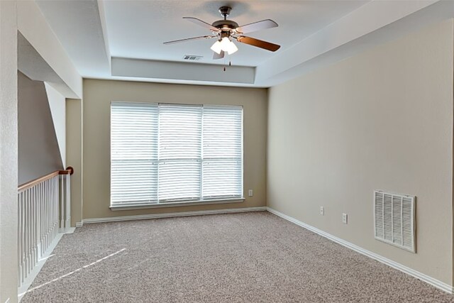 carpeted empty room with a tray ceiling and ceiling fan