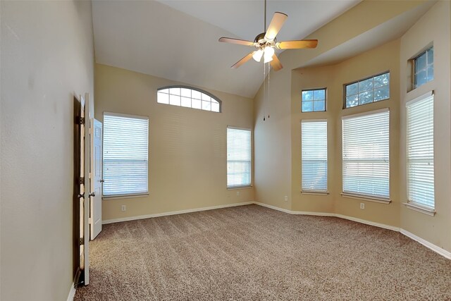 carpeted spare room featuring high vaulted ceiling, plenty of natural light, and ceiling fan