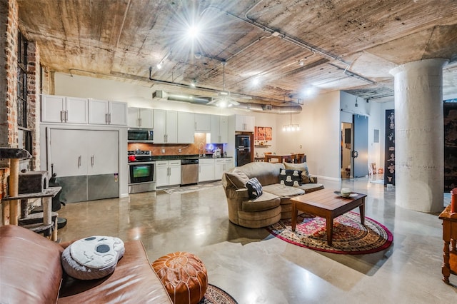 living room with concrete floors, decorative columns, and sink