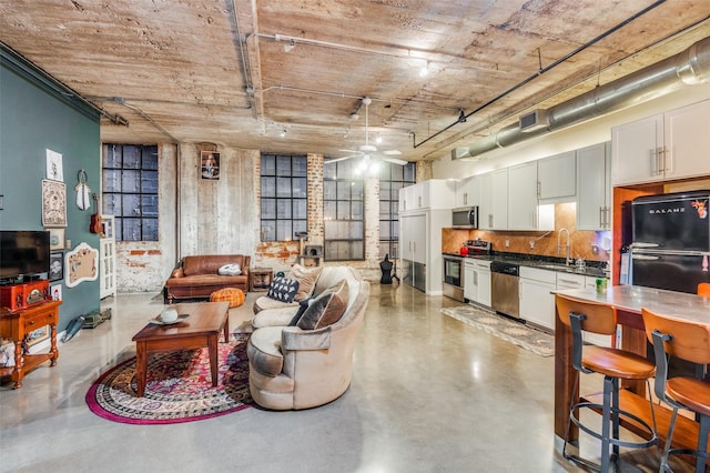 living room featuring ceiling fan, sink, and concrete floors