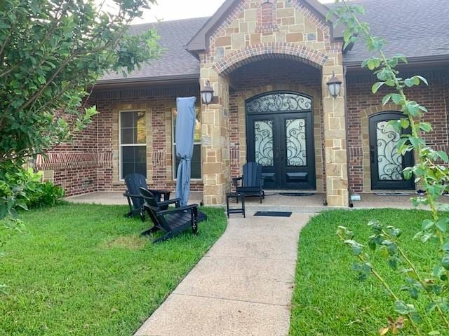 view of exterior entry with a yard and french doors