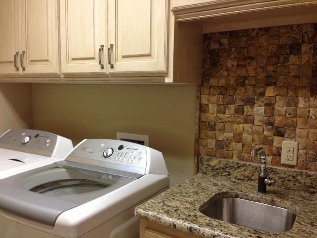 washroom with sink, washing machine and dryer, and cabinets