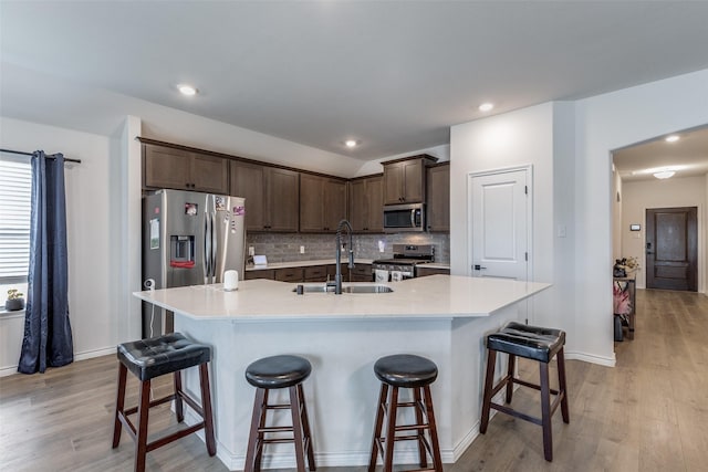 kitchen with sink, an island with sink, light hardwood / wood-style flooring, and appliances with stainless steel finishes