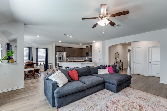 living room with ceiling fan, light wood-type flooring, and vaulted ceiling