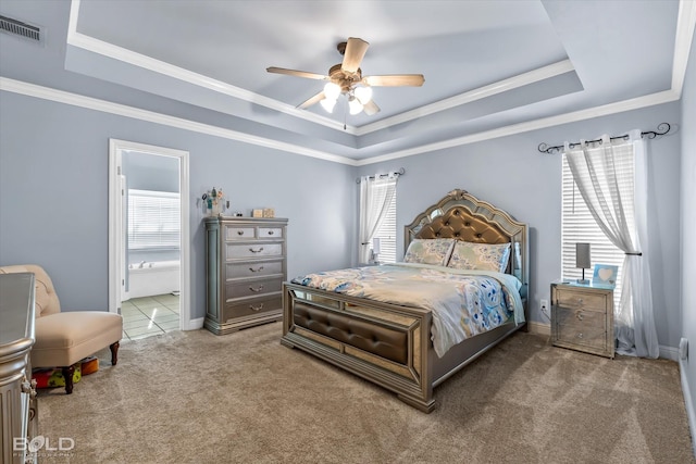 carpeted bedroom with ceiling fan, ensuite bath, and a tray ceiling