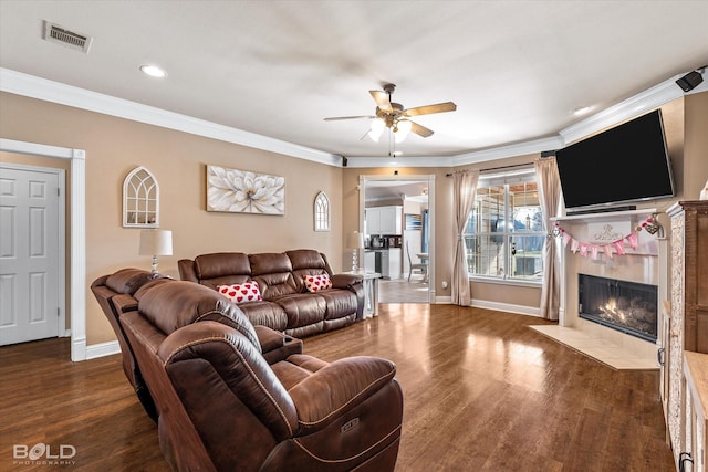 living room with a tiled fireplace, ceiling fan, dark hardwood / wood-style flooring, and ornamental molding