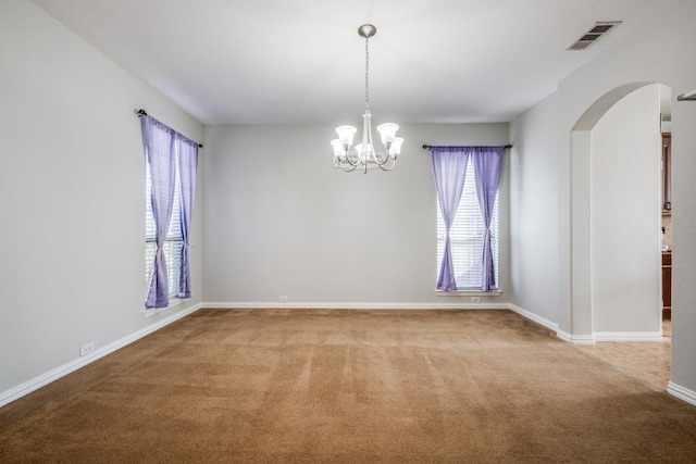 spare room featuring carpet flooring and a chandelier