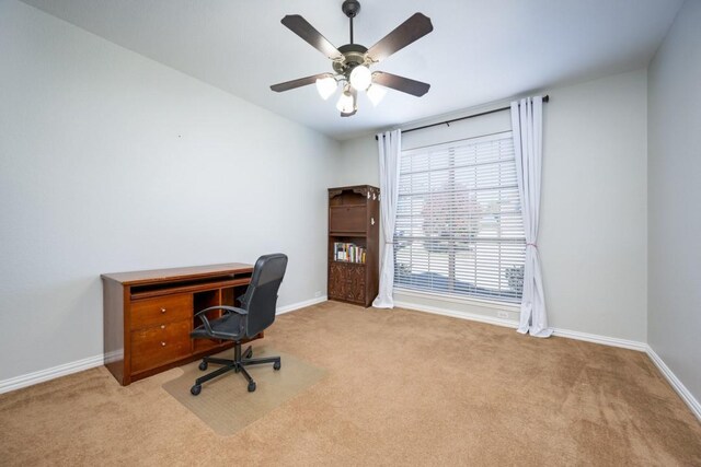 carpeted office with baseboards and a ceiling fan