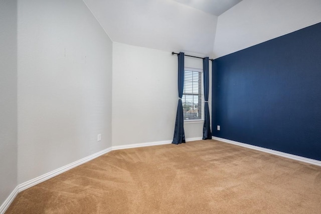 unfurnished room with lofted ceiling, baseboards, and carpet