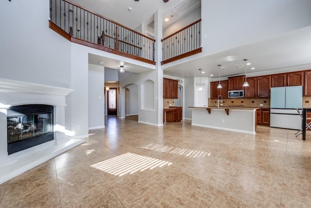 unfurnished living room featuring ceiling fan, a towering ceiling, and sink