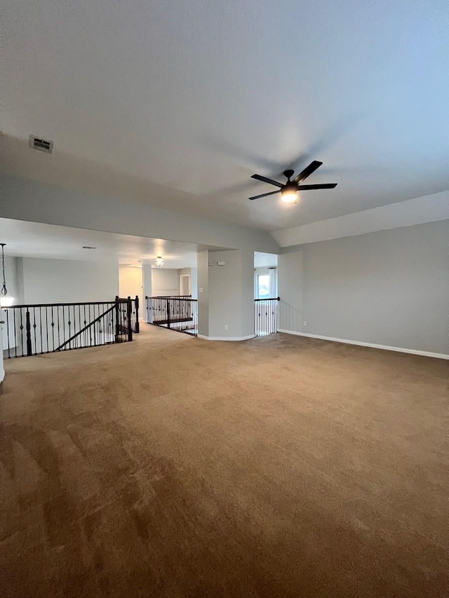 carpeted spare room featuring baseboards, visible vents, and a ceiling fan