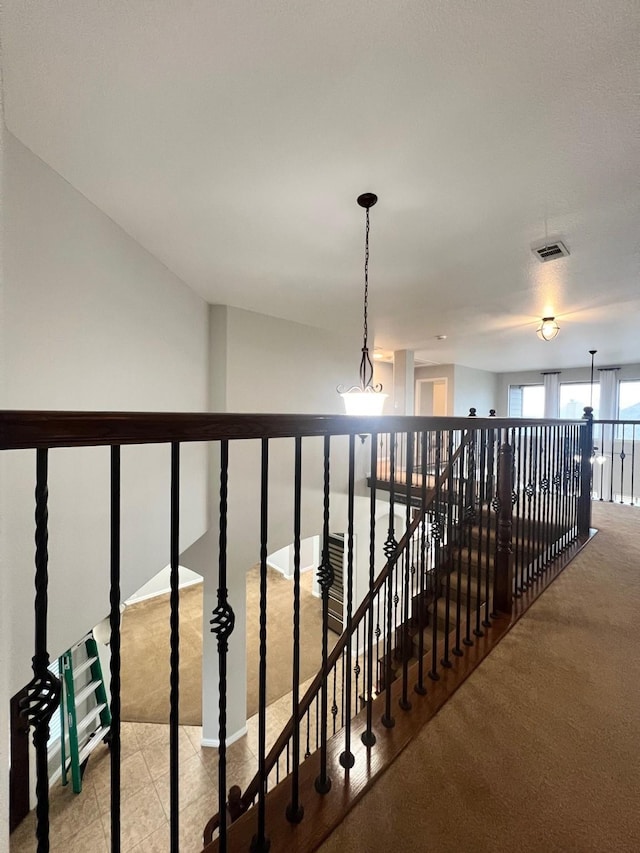 hall with carpet, visible vents, and an upstairs landing