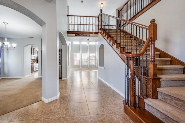 tiled entryway with a towering ceiling and a chandelier