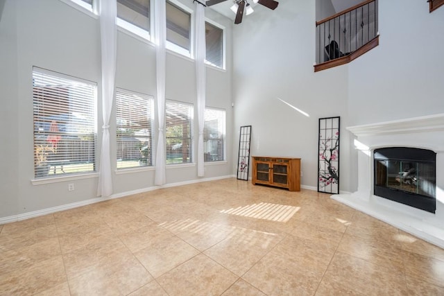 unfurnished living room with ceiling fan, a towering ceiling, and light tile patterned flooring