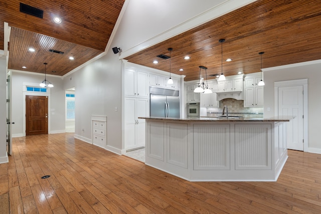 kitchen featuring white cabinets, decorative light fixtures, a spacious island, and appliances with stainless steel finishes