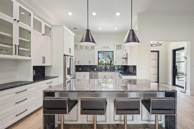 kitchen with a kitchen bar, stainless steel appliances, a kitchen island, and hanging light fixtures