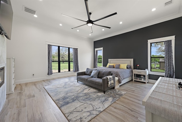 bedroom featuring a fireplace, light hardwood / wood-style flooring, and ceiling fan