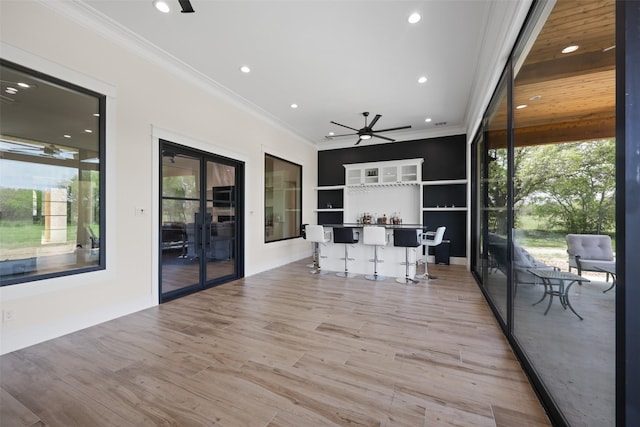 interior space with french doors, ornamental molding, ceiling fan, white cabinets, and light hardwood / wood-style floors