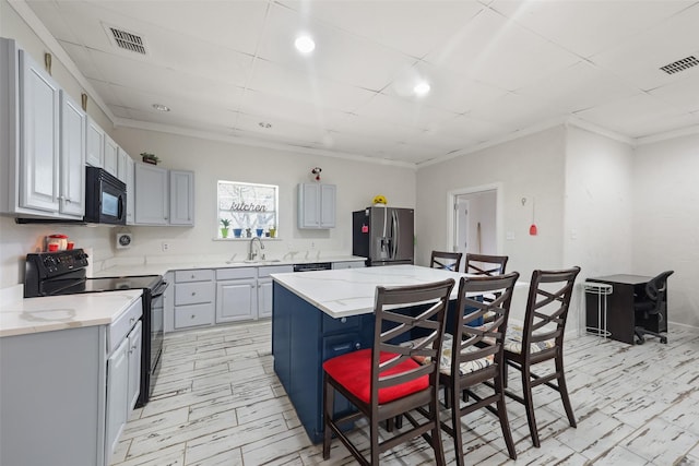 kitchen featuring sink, a kitchen bar, a kitchen island, black appliances, and ornamental molding