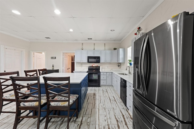 kitchen featuring a drop ceiling, black appliances, blue cabinets, sink, and white cabinetry