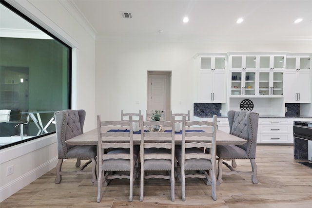 dining room with light hardwood / wood-style flooring and ornamental molding