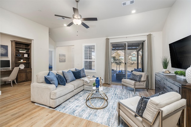 living room featuring ceiling fan, lofted ceiling, light wood-type flooring, and built in shelves