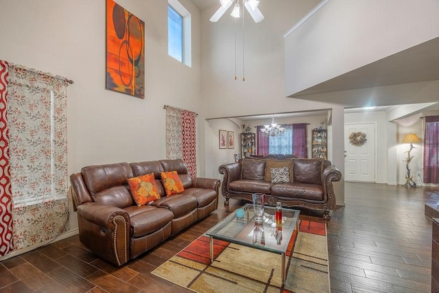 living room featuring dark wood-type flooring, ceiling fan with notable chandelier, and a towering ceiling