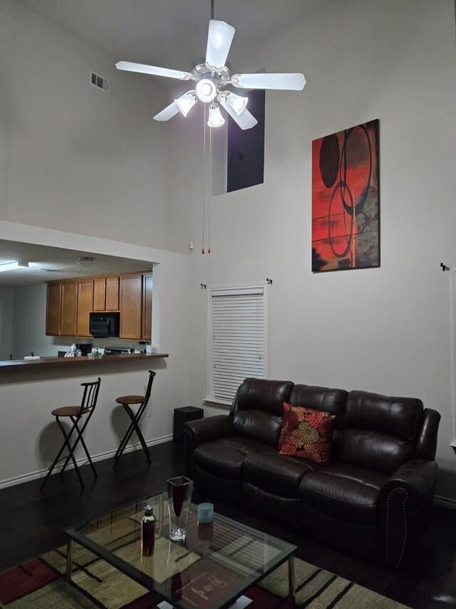 living room with a towering ceiling and ceiling fan with notable chandelier