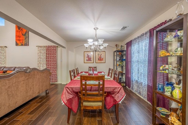 dining area with an inviting chandelier, a textured ceiling, and dark hardwood / wood-style floors