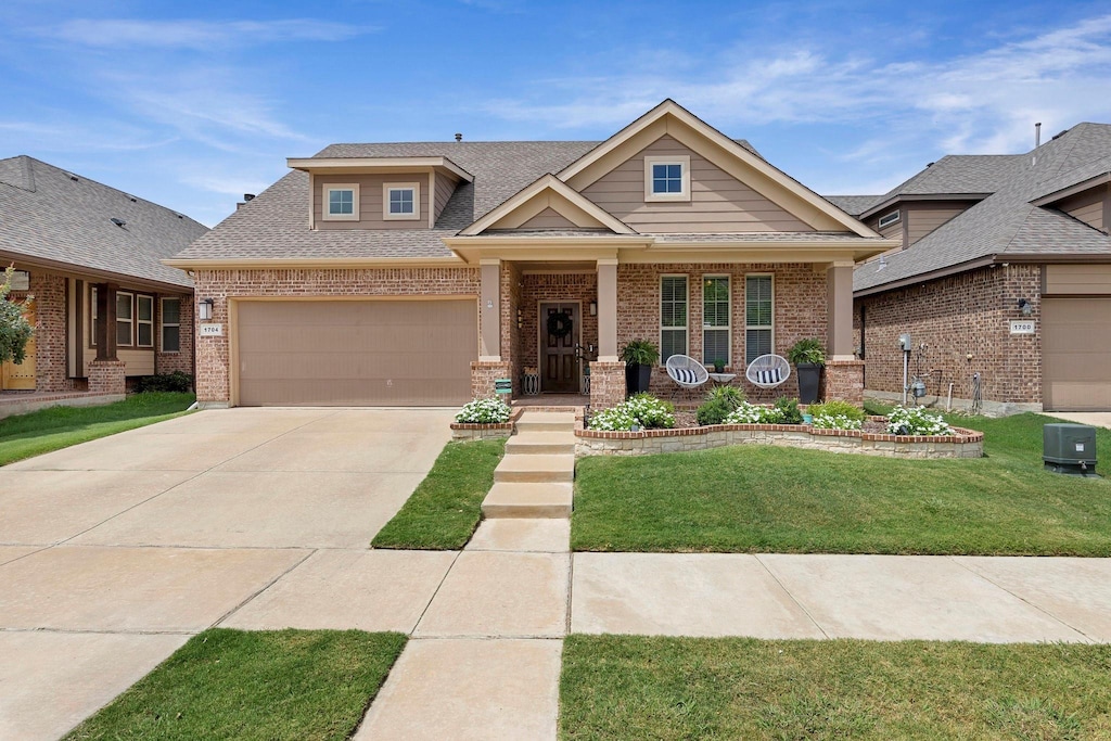 craftsman-style home featuring a front yard, covered porch, and a garage