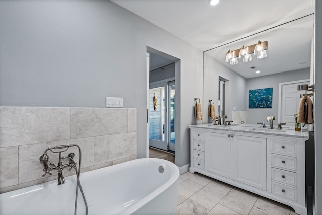 bathroom with a bathing tub, vanity, and tile patterned floors