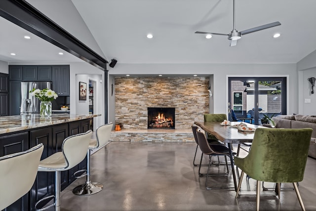 dining space featuring ceiling fan, a fireplace, and vaulted ceiling