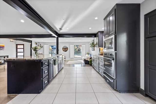 kitchen featuring appliances with stainless steel finishes, light stone counters, beamed ceiling, a kitchen island, and light tile patterned flooring