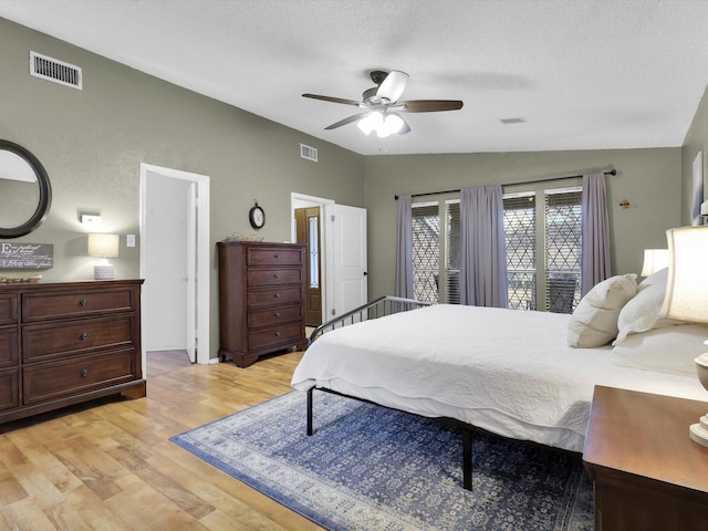 bedroom featuring ceiling fan, lofted ceiling, light hardwood / wood-style flooring, and a textured ceiling