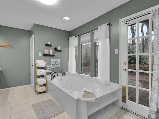 bathroom with a tub to relax in, tile patterned flooring, and a textured ceiling