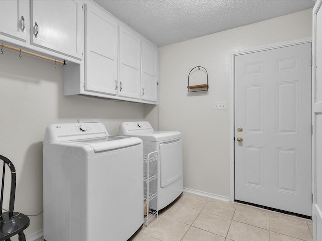 laundry room with cabinets, washing machine and dryer, light tile patterned floors, and a textured ceiling