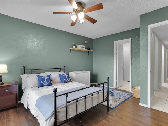 bedroom with wood-type flooring, ceiling fan, and a textured ceiling