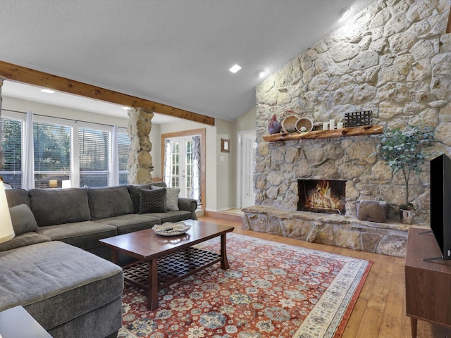 living room with a stone fireplace, vaulted ceiling, and light wood-type flooring