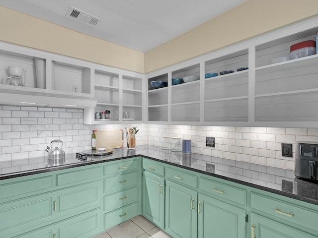 kitchen featuring backsplash, dark stone counters, green cabinetry, and light tile patterned flooring