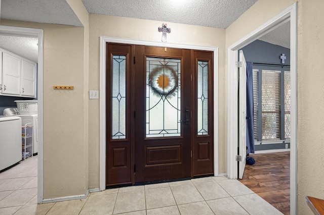 tiled entryway featuring washer and dryer and a textured ceiling