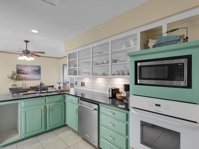 kitchen with sink, light tile patterned floors, green cabinets, appliances with stainless steel finishes, and tasteful backsplash