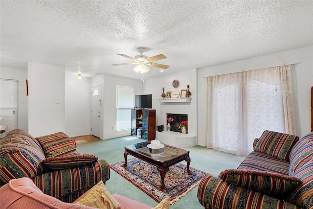 living room featuring ceiling fan, light colored carpet, a textured ceiling, and a brick fireplace