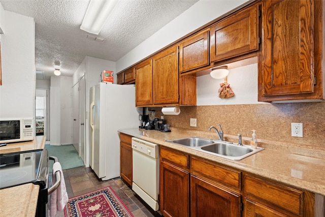 kitchen with a textured ceiling, decorative backsplash, white appliances, and sink