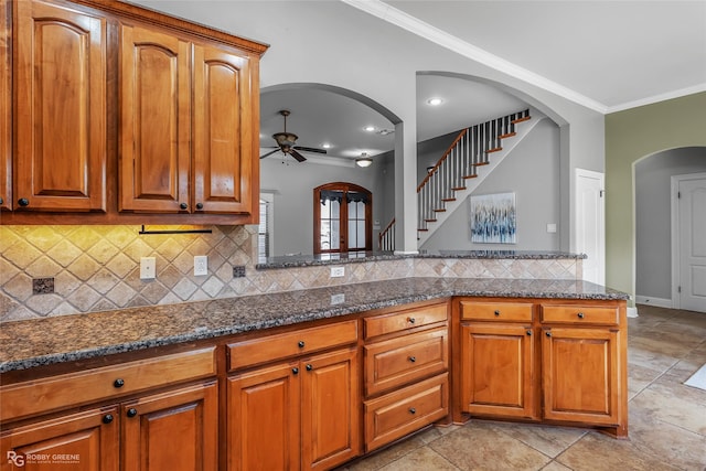 kitchen with dark stone countertops, crown molding, ceiling fan, and light tile patterned flooring