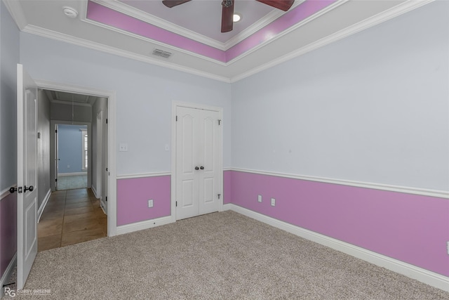 unfurnished bedroom with carpet, a raised ceiling, ceiling fan, and ornamental molding