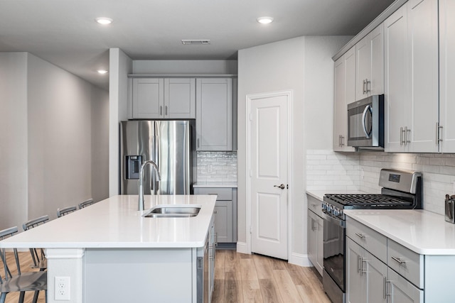 kitchen featuring a center island with sink, backsplash, a kitchen bar, and stainless steel appliances