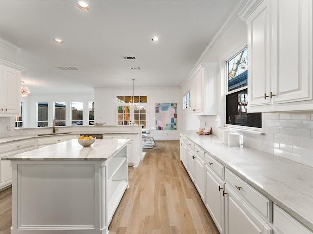 kitchen with sink, ornamental molding, tasteful backsplash, a kitchen island, and white cabinetry