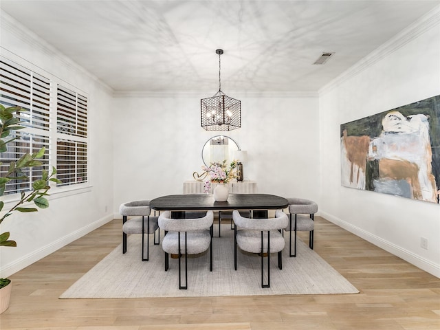 dining area featuring light hardwood / wood-style floors, crown molding, and an inviting chandelier