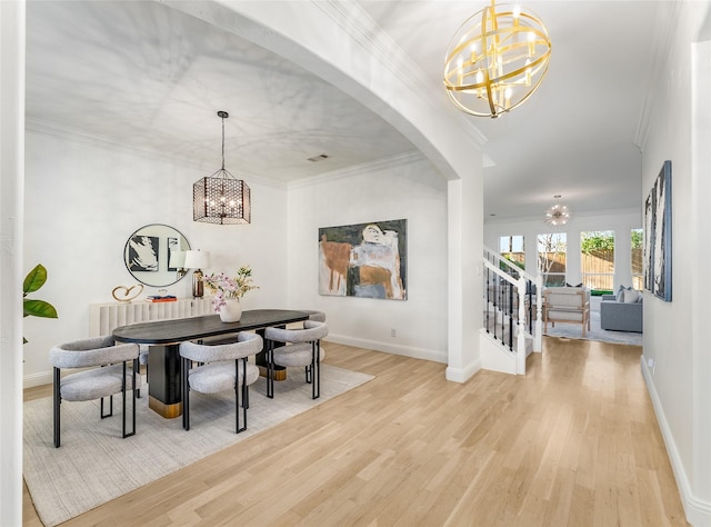 dining space with wood-type flooring, an inviting chandelier, and crown molding